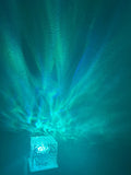 Teal wave light spreading up a dark wall from the cordless cube