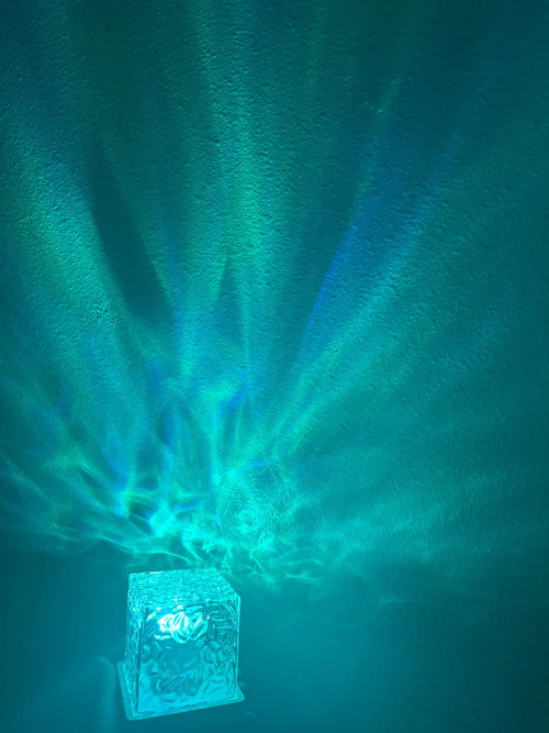 Teal wave light spreading up a dark wall from the cordless cube