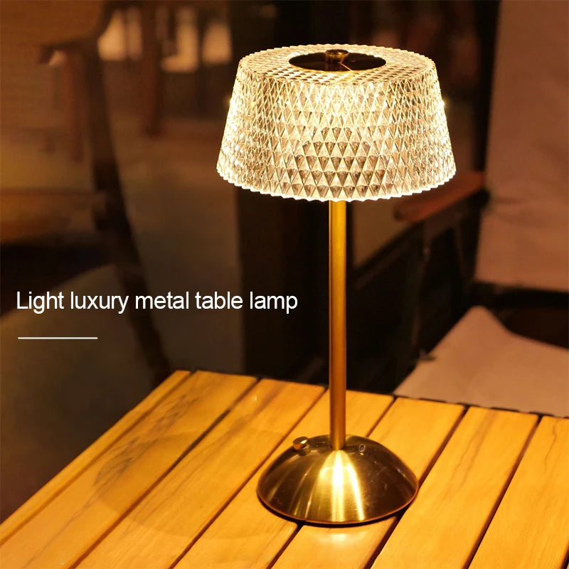 Faceted glass shade and gold stem of the dome lamp on a wooden table