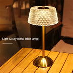 Faceted glass shade and gold stem of the dome lamp on a wooden table