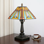 Pyramid lamp on a table next to a teacup, curtains behind