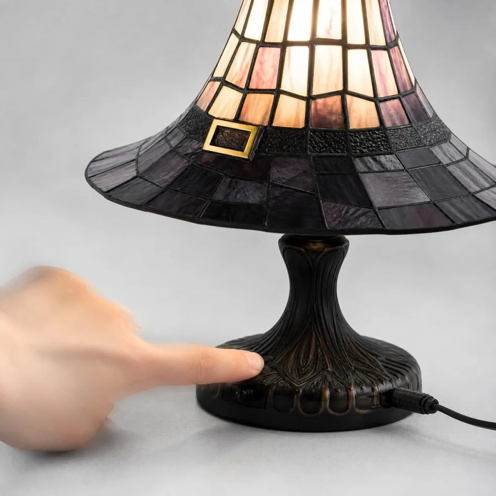 A finger on the base of the witch hat lamp, showing the carved stand and the cord