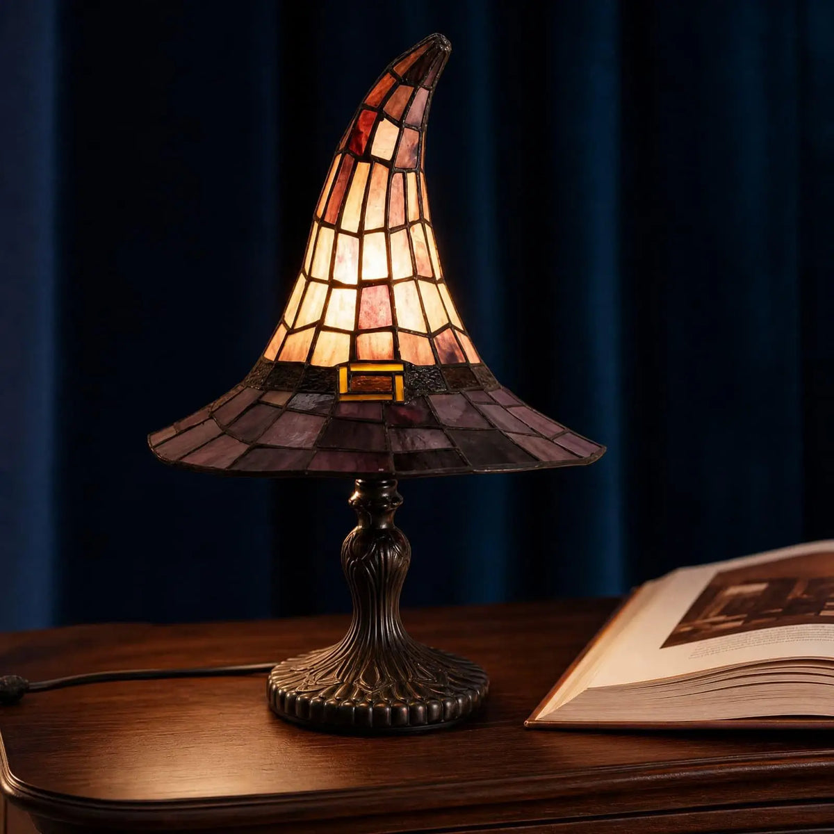 Witch hat lamp lit on a wooden desk, amber and plum panels glowing, a book beside it