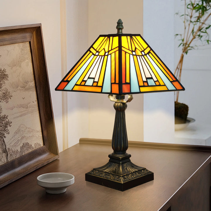 The pyramid lamp lit on a sideboard beside a framed painting