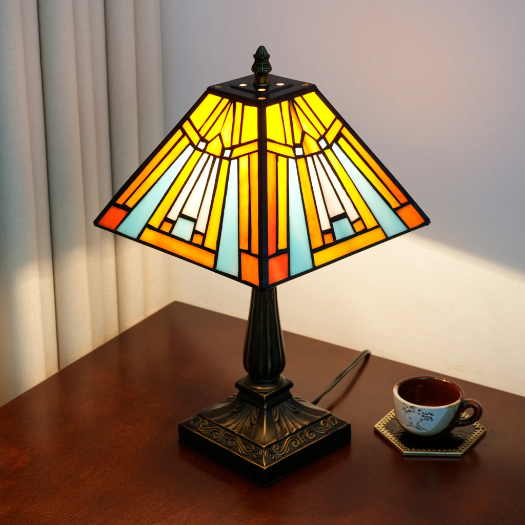 Lit pyramid lamp from the side, showing the square shade and the bronze-look base