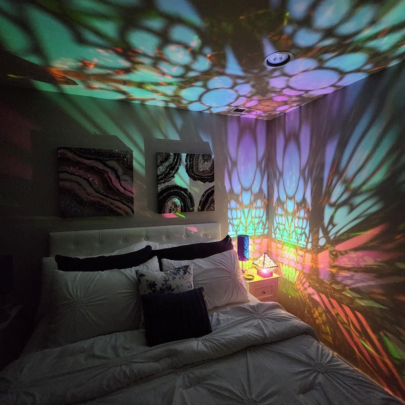 A bedroom at night, arches and circles of colored light over the walls and ceiling, all from one Cathedral on the nightstand
